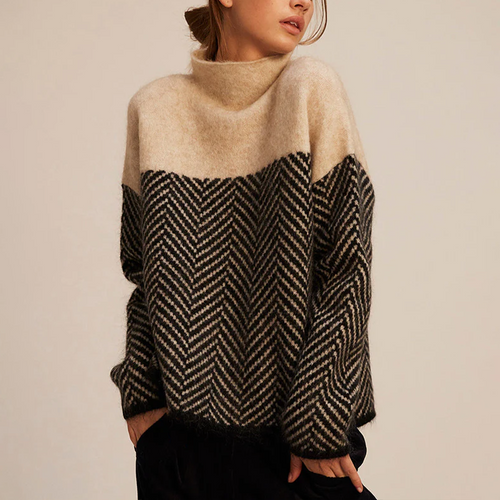 Woman wearing a beige and charcoal color-block knit sweater with a mock neck, herringbone pattern, long sleeves, and a relaxed fit.