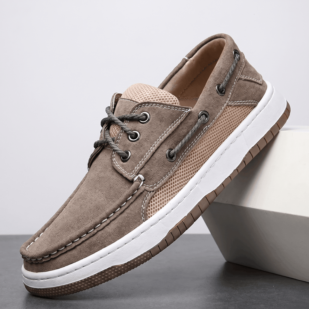 Single gray suede Adrian boat shoe with tan mesh side panel and white sole, tilted against a white block on a gray surface