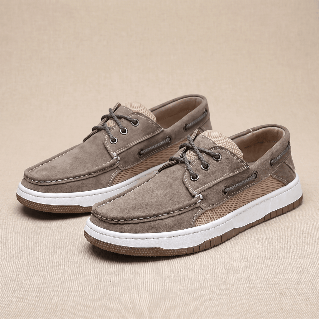 Pair of gray suede Adrian boat shoes with tan mesh panels, placed side by side on a beige surface