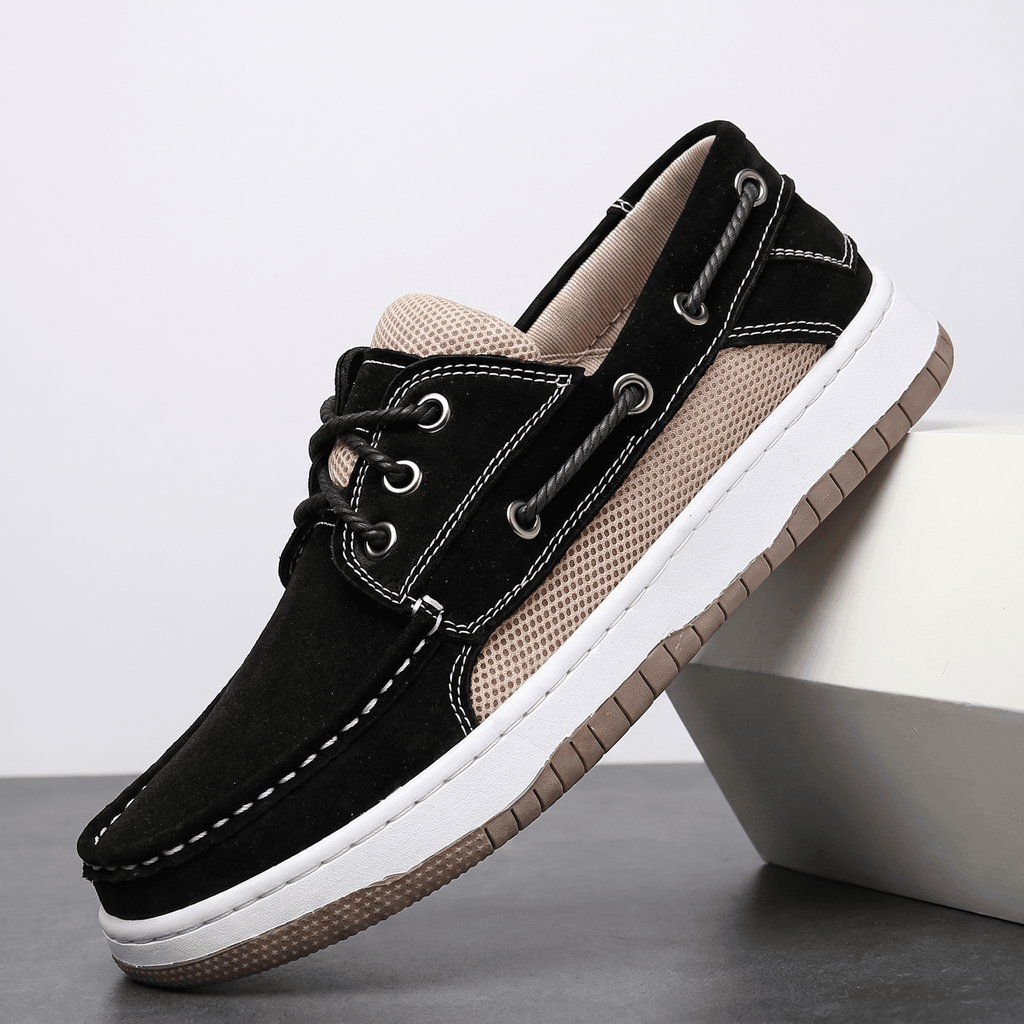 Single black suede Adrian boat shoe with beige mesh side panel and white sole, tilted against a white block