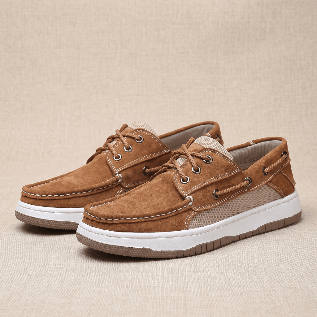 Pair of tan suede Adrian boat shoes with beige mesh panels and white soles, placed side by side on a woven beige surface