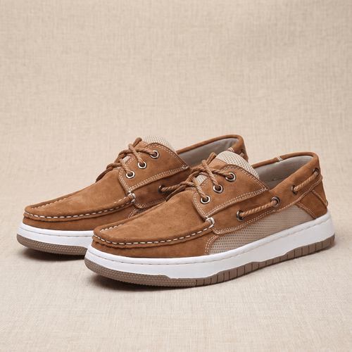 Pair of tan suede Adrian boat shoes with beige mesh panels and white soles, placed side by side on a woven beige surface