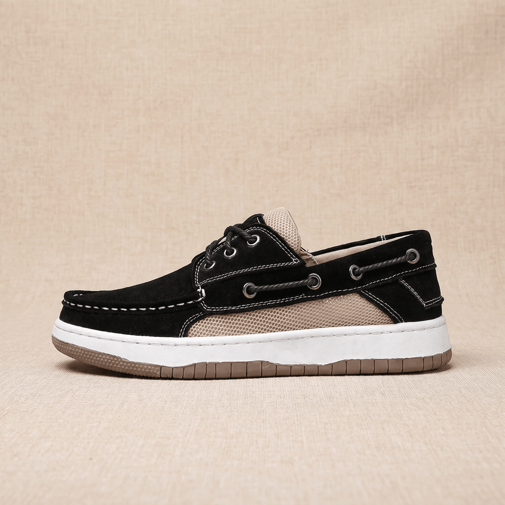 Black suede Adrian boat shoe facing left, showing the beige mesh panel, rope laces, and white-to-tan layered sole