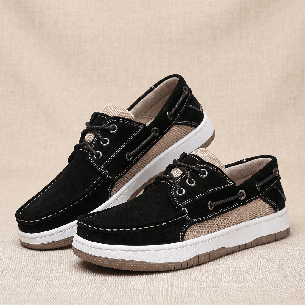 Pair of black suede Adrian boat shoes with beige mesh panels, placed side by side on a beige surface