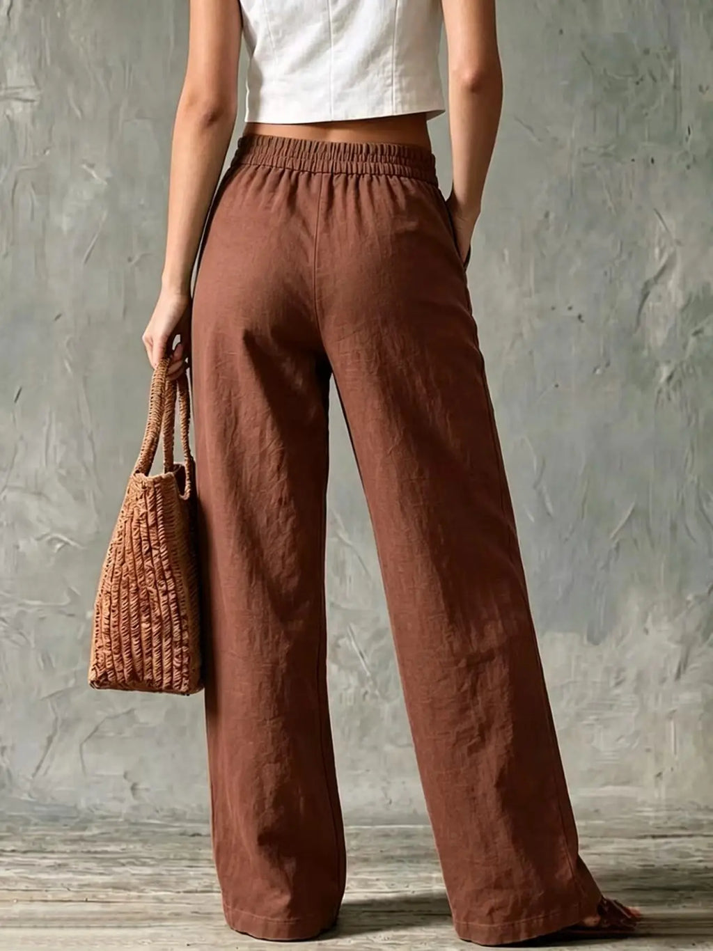 Women's chocolate brown high-waisted wide-leg linen pants featuring front pleats, side pockets, and a loose silhouette.