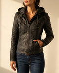 Woman modeling the Aria black leather moto jacket with hood, zip-front closure, and fitted silhouette
