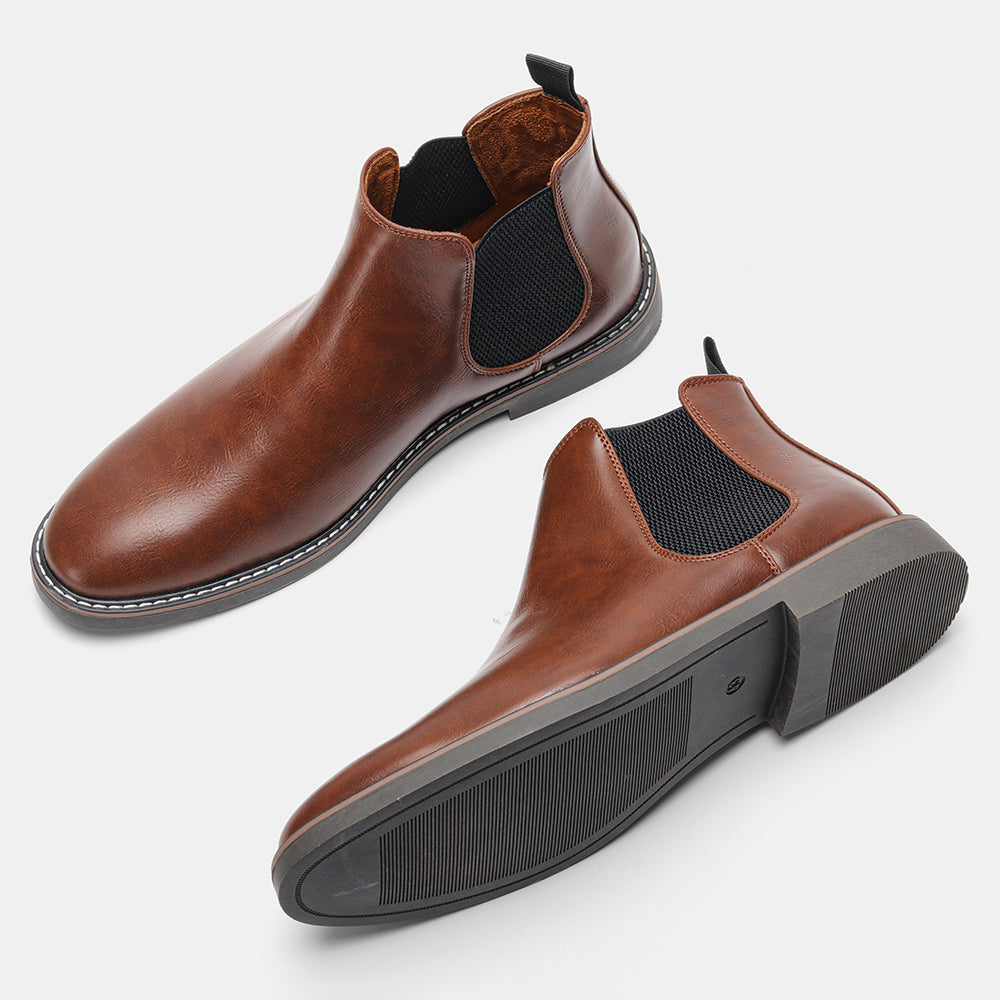 Pair of brown leather Chelsea boots, one tipped over to display the tread sole, on a plain white background.