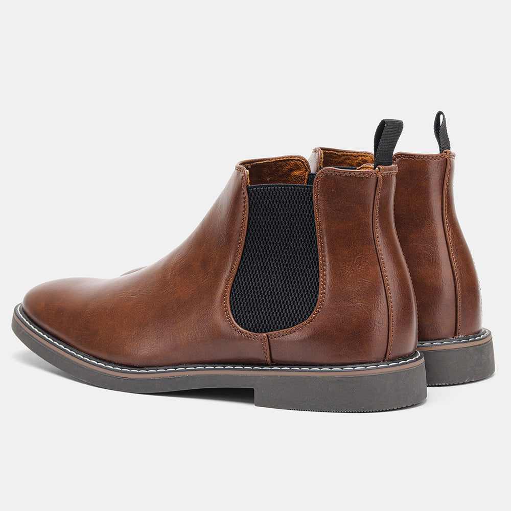 Close-up of a pair of brown leather Chelsea boots, one tilted forward to show the tread sole in detail, on a plain white background.