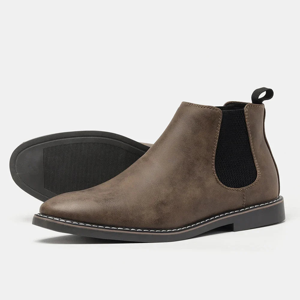 A single taupe leather Chelsea boot with an elastic side panel and pull tab, shown on its side on a plain white background to display the tread sole.