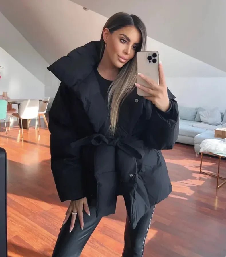 Black oversized puffer jacket in quilted shell with a high stand collar and self-tie waist belt for a cinched silhouette.