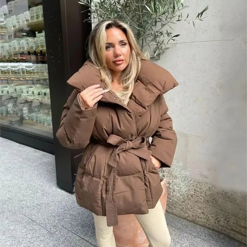 Brown quilted puffer jacket with an exaggerated stand collar and a self-tie waist belt cinched over a relaxed fit.
