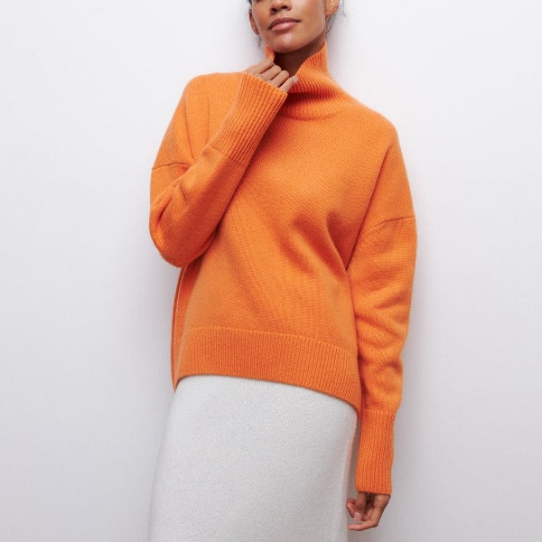 Woman wearing an orange oversized ribbed turtleneck sweater with short sleeves and a relaxed silhouette.
