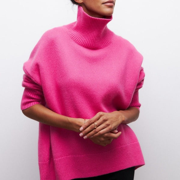 Woman wearing a hot pink oversized ribbed turtleneck sweater with short sleeves and a modern relaxed silhouette.