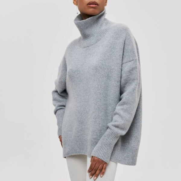 Woman wearing a light gray oversized ribbed turtleneck sweater with short sleeves and a relaxed fit.
