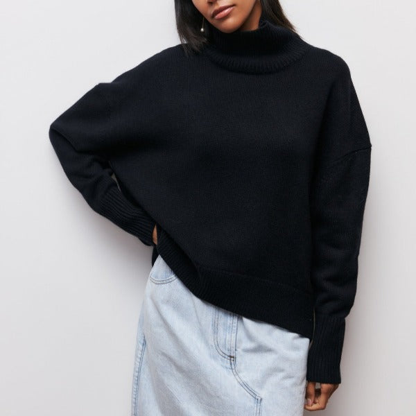 Woman wearing a black oversized ribbed turtleneck sweater featuring short sleeves and a contemporary relaxed silhouette.
