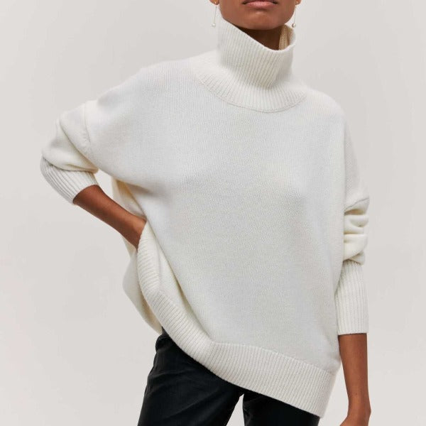 Woman wearing a white oversized ribbed turtleneck sweater with short sleeves and a soft relaxed fit.