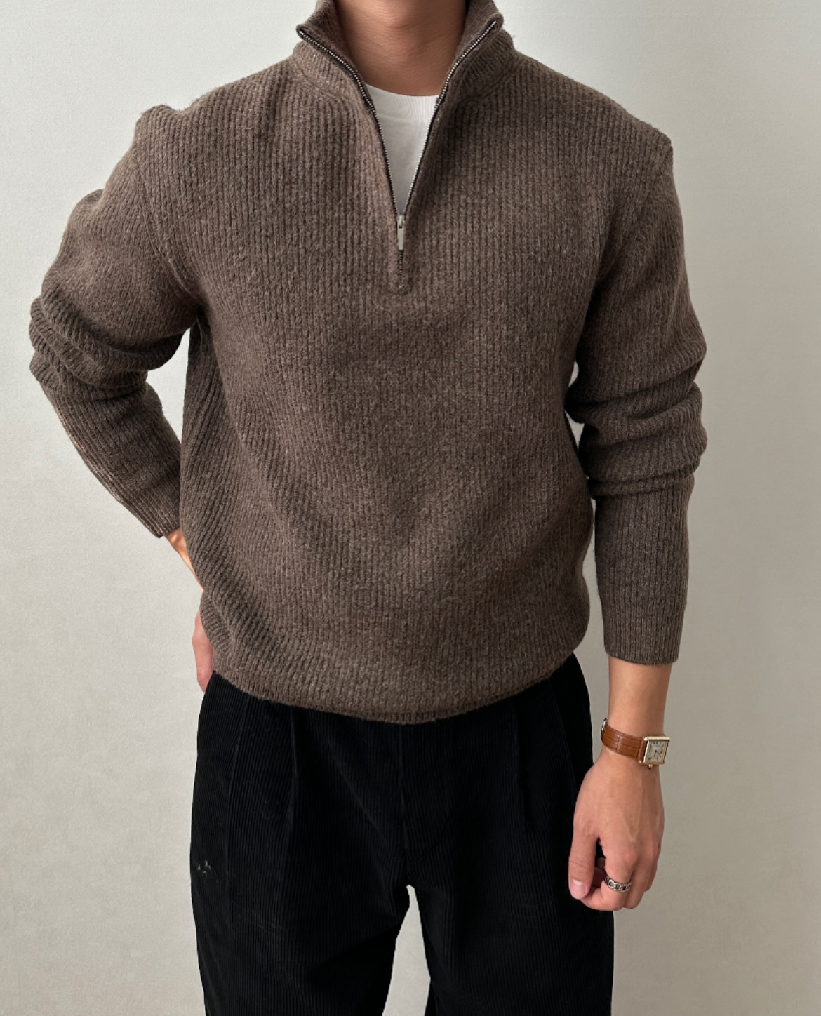 Brown brushed rib-knit quarter-zip sweater with a stand collar, worn over a white tee with black trousers.