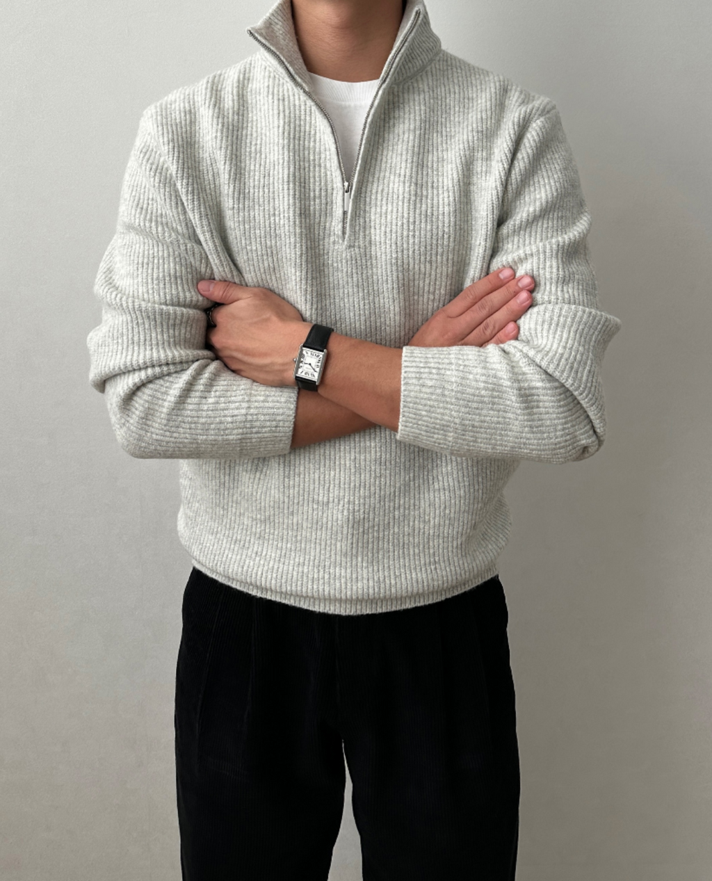 Light gray brushed rib-knit quarter-zip sweater with a stand collar, worn over a white tee with black trousers.