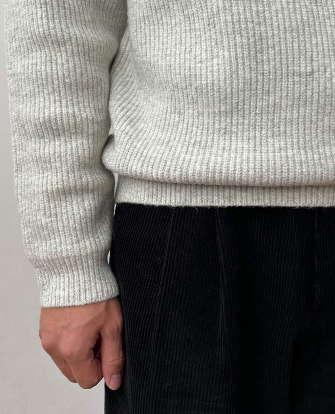 Light gray brushed rib-knit sweater with a regular fit, paired with black corduroy trousers.