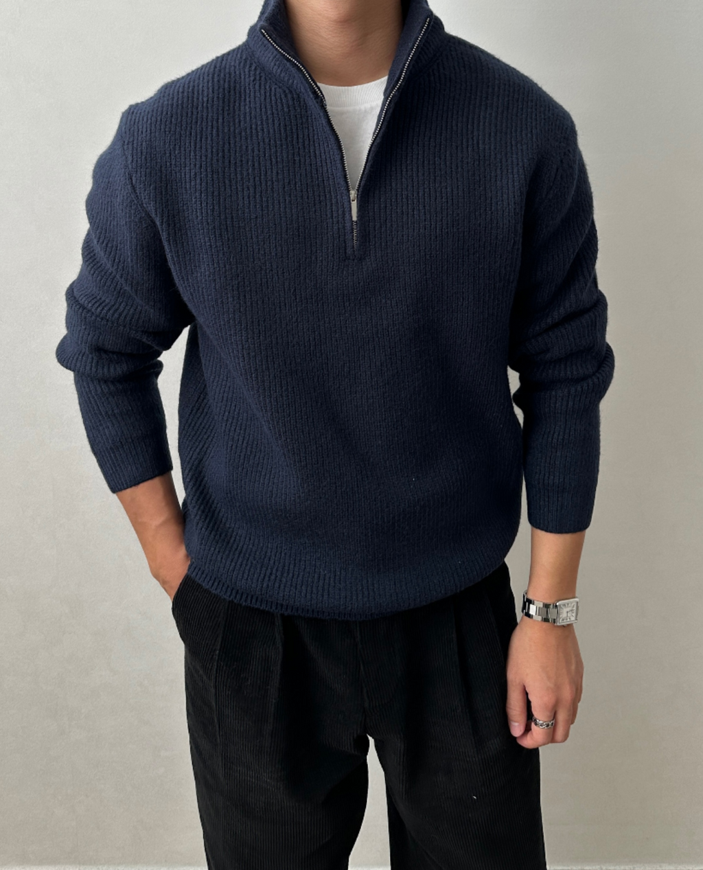 Navy blue brushed rib-knit quarter-zip sweater with a stand collar, worn over a white tee and paired with black trousers.