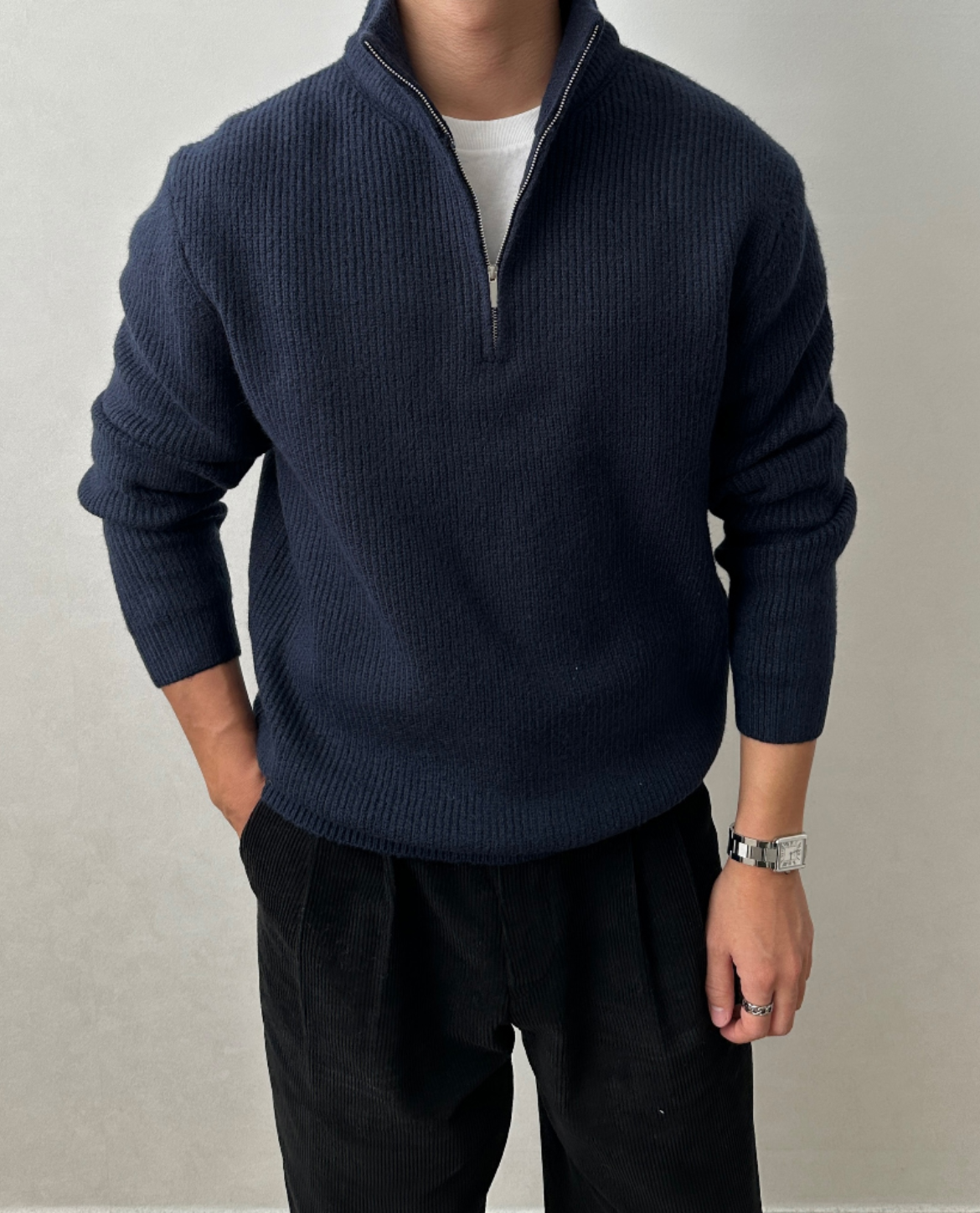 Navy blue brushed rib-knit quarter-zip sweater with a stand collar, worn over a white tee and paired with black trousers.