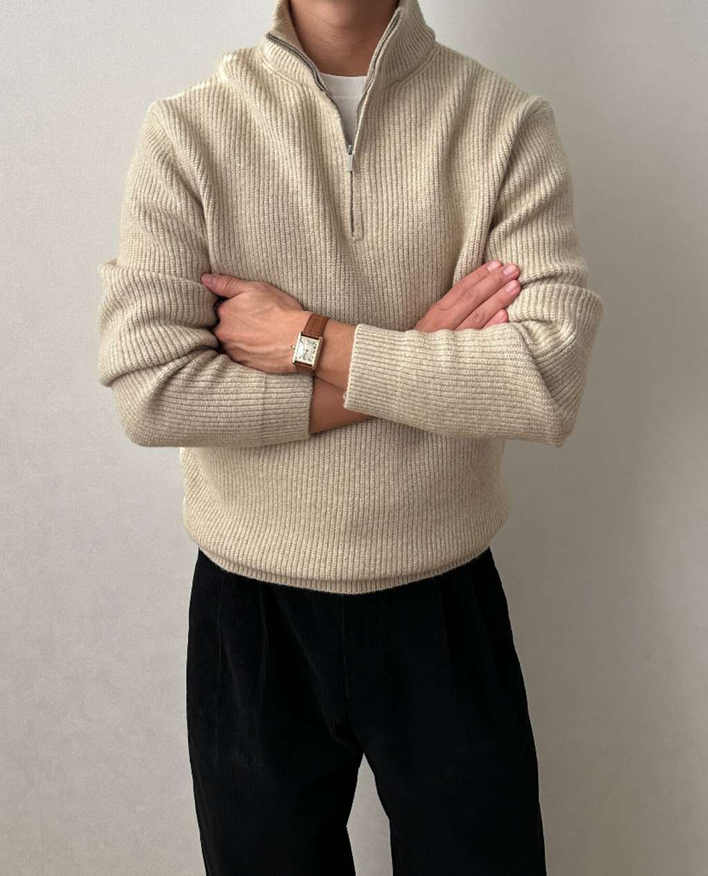 Beige brushed rib-knit quarter-zip sweater with a stand collar, worn over a white tee and black trousers.