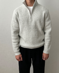 Light gray brushed rib-knit quarter-zip sweater with a stand collar, worn over a white tee and black trousers.