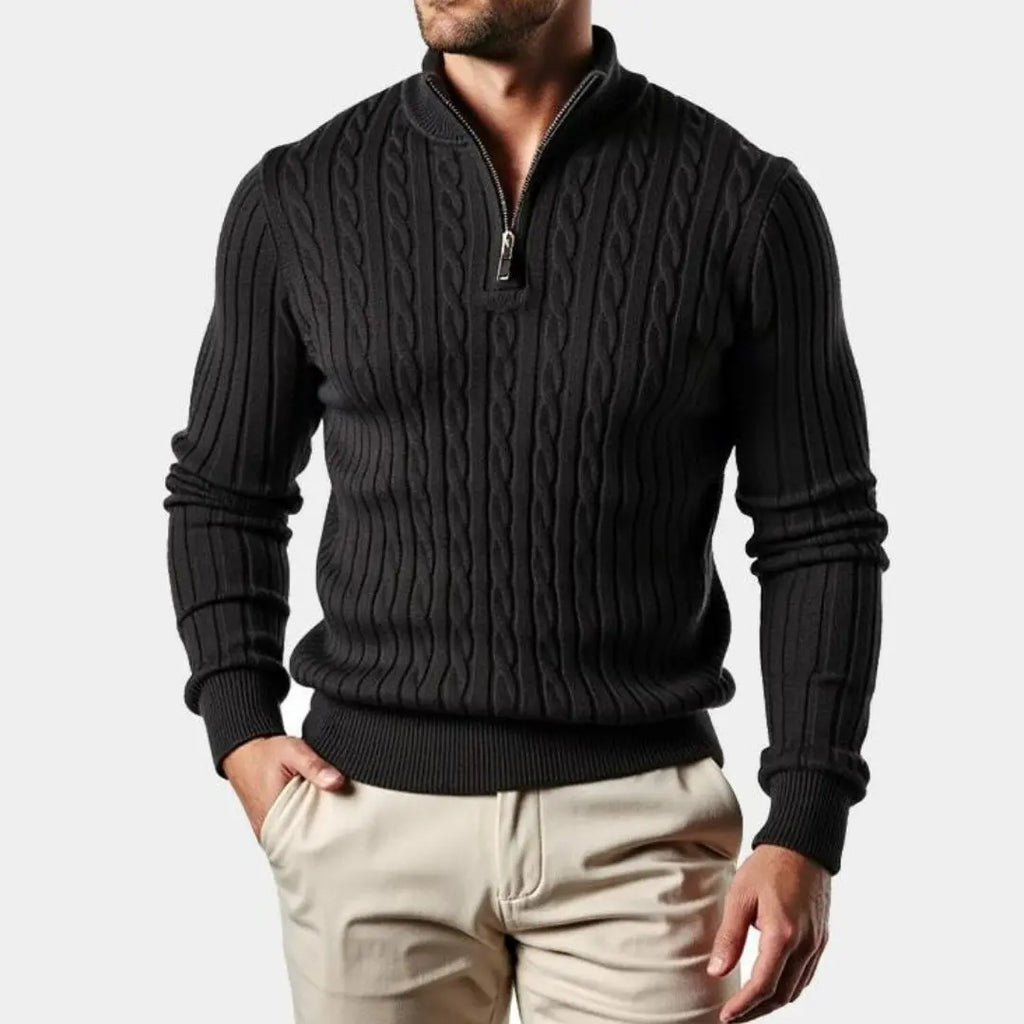 Black cable knit quarter-zip sweater with a ribbed mock neck, tailored fit, and silver hardware, worn with light chinos.