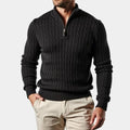 Black cable knit quarter-zip sweater with a ribbed mock neck, tailored fit, and silver hardware, worn with light chinos.