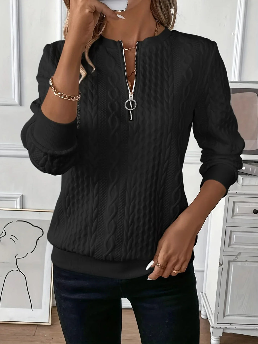 Black cable knit quarter-zip sweater with a metal ring-pull neckline, ribbed cuffs, and a banded hem.