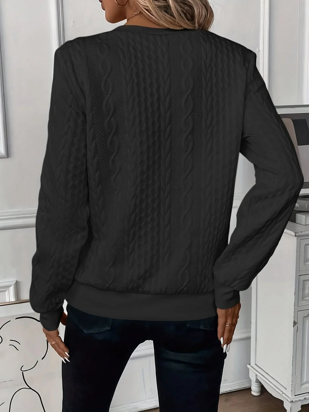 Black cable knit quarter-zip sweater with textured panels, ribbed cuffs, and a banded hem worn with dark jeans.