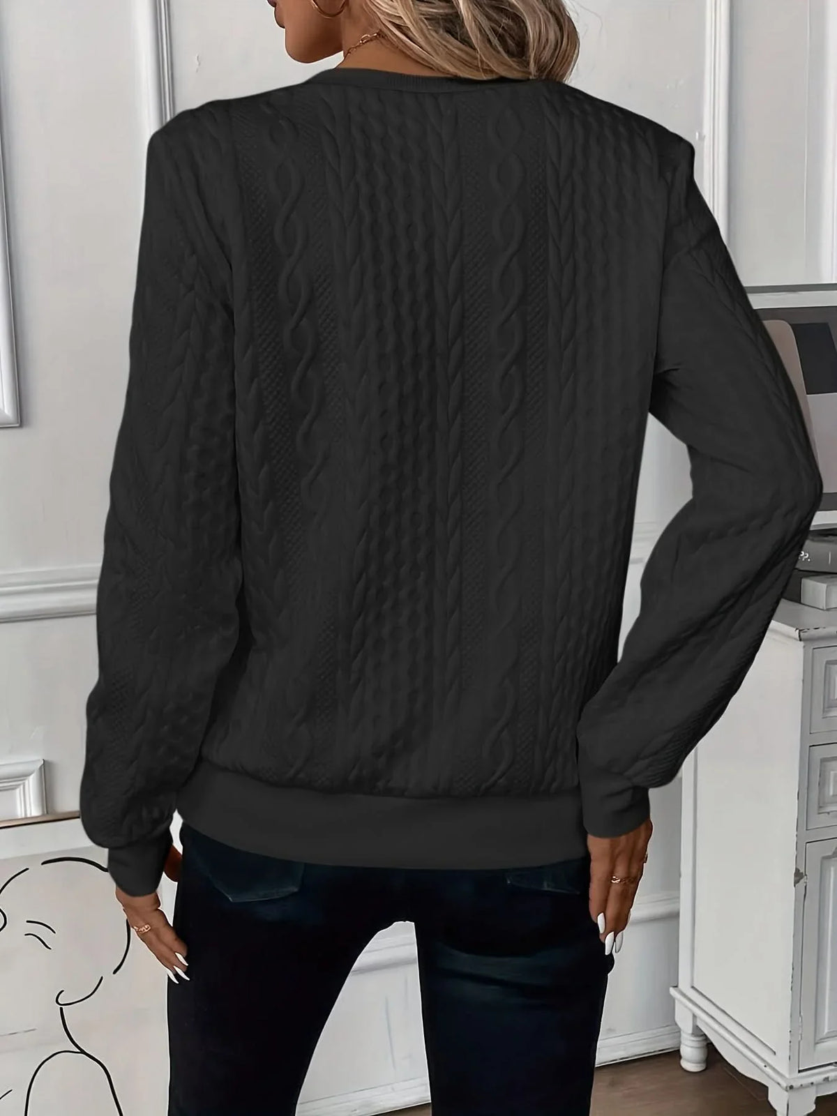Black cable knit quarter-zip sweater with textured panels, ribbed cuffs, and a banded hem worn with dark jeans.