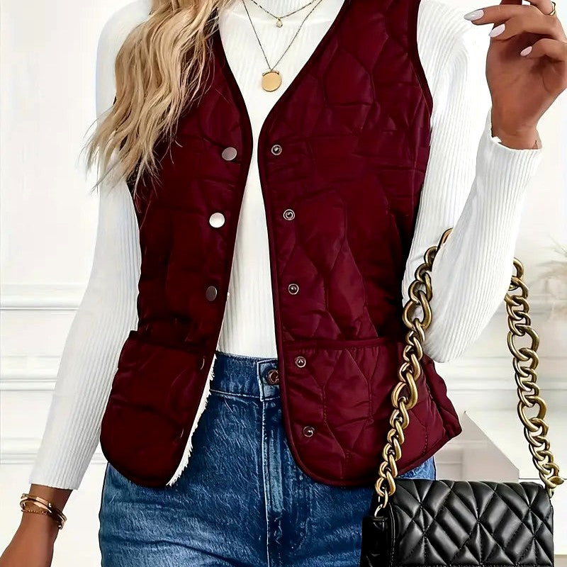 Front view of a women's red quilted puffer vest with a sleeveless design, snap-button closure, and side pockets.