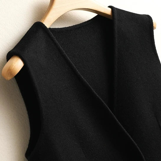 Close-up of the V-neckline and soft knit fabric on a women's black wrap sweater vest.