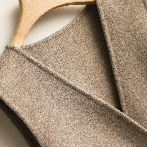 Close-up of the wrap lapel and textured knit fabric on a women's beige sleeveless sweater vest.