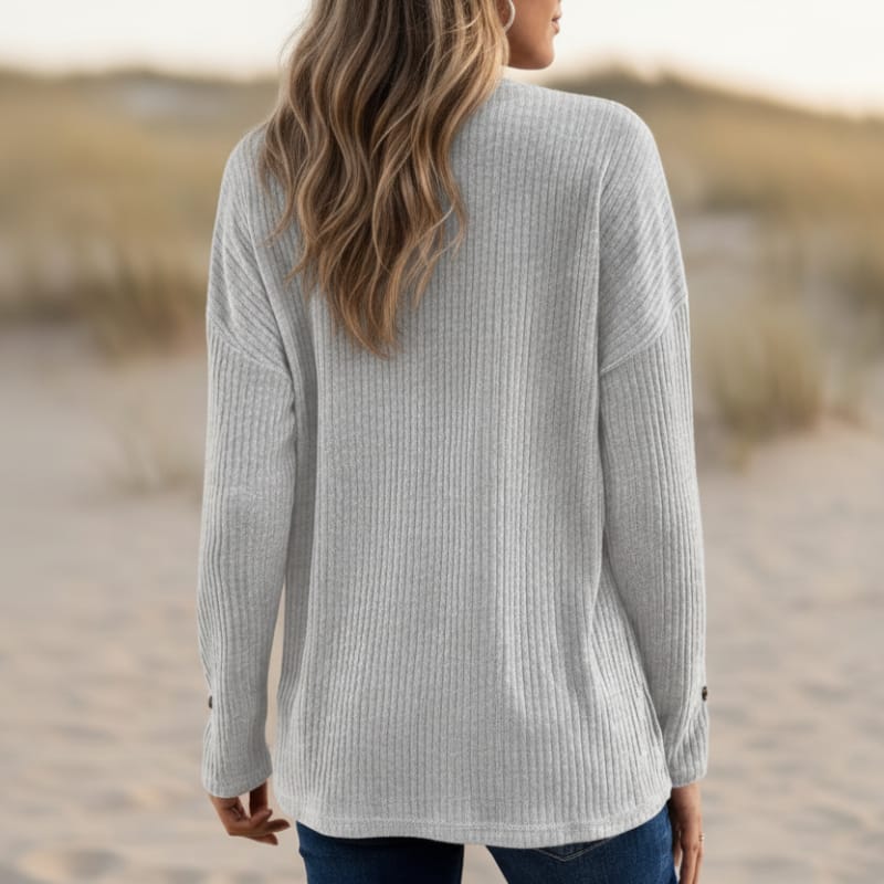 Back view of a woman wearing a light gray waffle knit Henley sweater with a collared neckline, long sleeves, and a relaxed fit.
