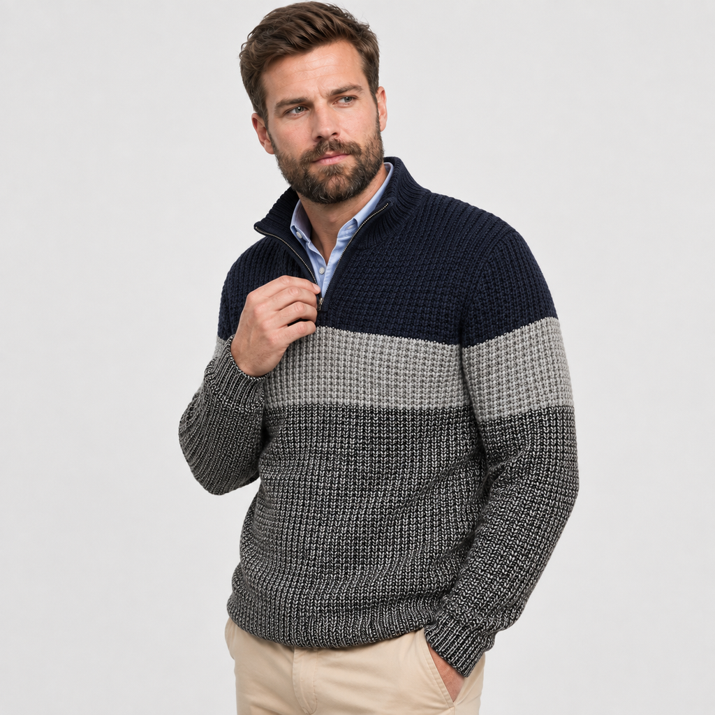 Chunky knit quarter-zip sweater in navy and grey colorblock stripes with a stand collar, layered over a light blue shirt.