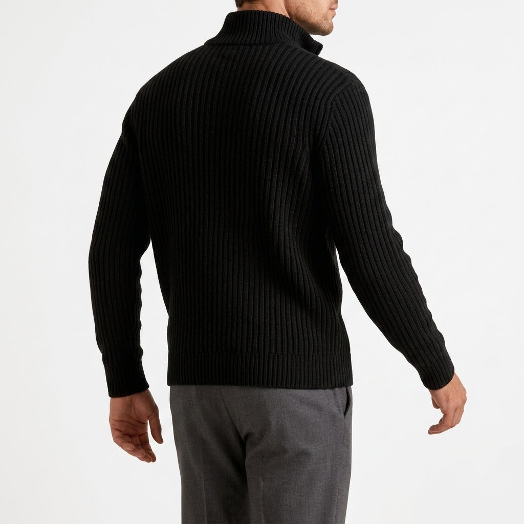 Black chunky ribbed quarter-zip sweater with a high stand collar, worn in a relaxed fit over grey trousers.