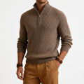 Taupe chunky ribbed quarter-zip sweater in heavyweight knit with a high stand collar and metal zipper, worn with tan chinos.