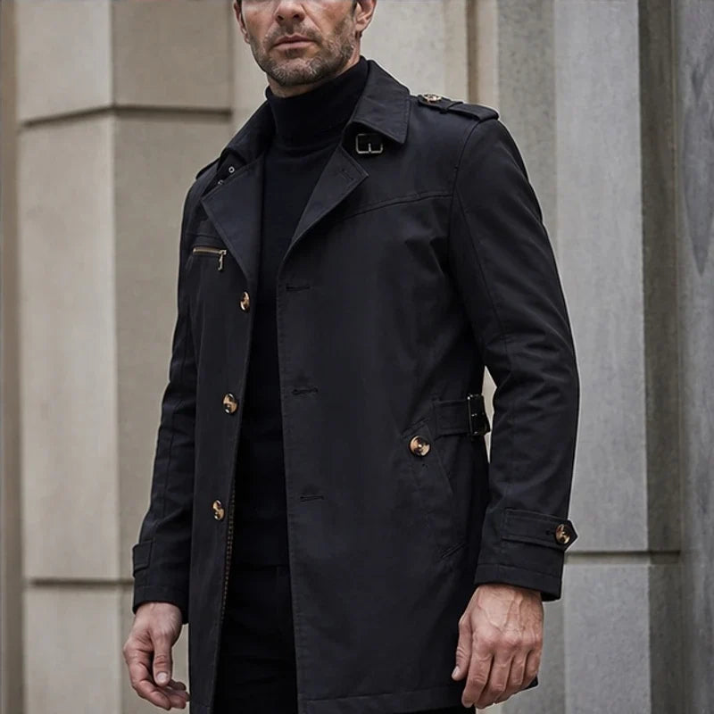 Black cotton-blend trench coat with notched lapels, shoulder epaulettes, button front, and belted waist.