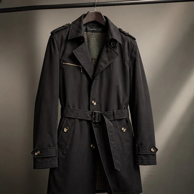 Black cotton-blend trench coat with a belted waist, notched lapels, shoulder epaulettes, and a zip chest pocket.