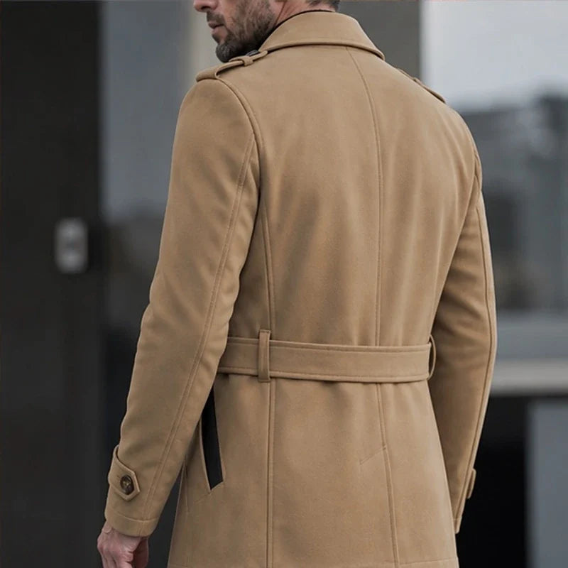 Tan cotton-blend trench coat featuring a belted waist, shoulder epaulettes, and buckled cuffs in a structured, tailored fit.