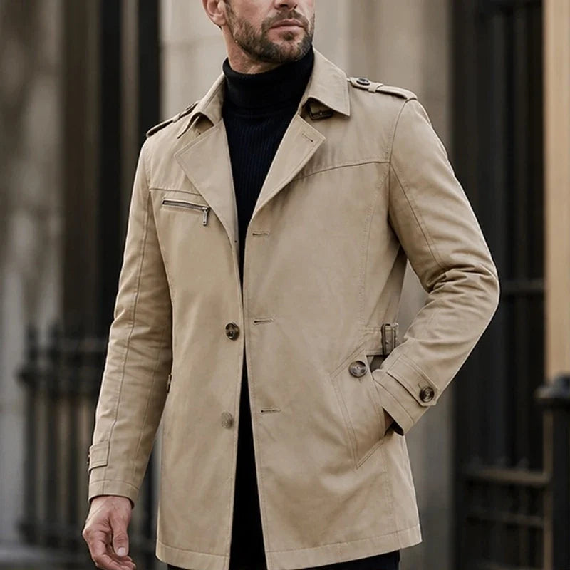 Beige cotton-blend trench coat featuring a notched lapel, button front, shoulder epaulettes, and a zip chest pocket.