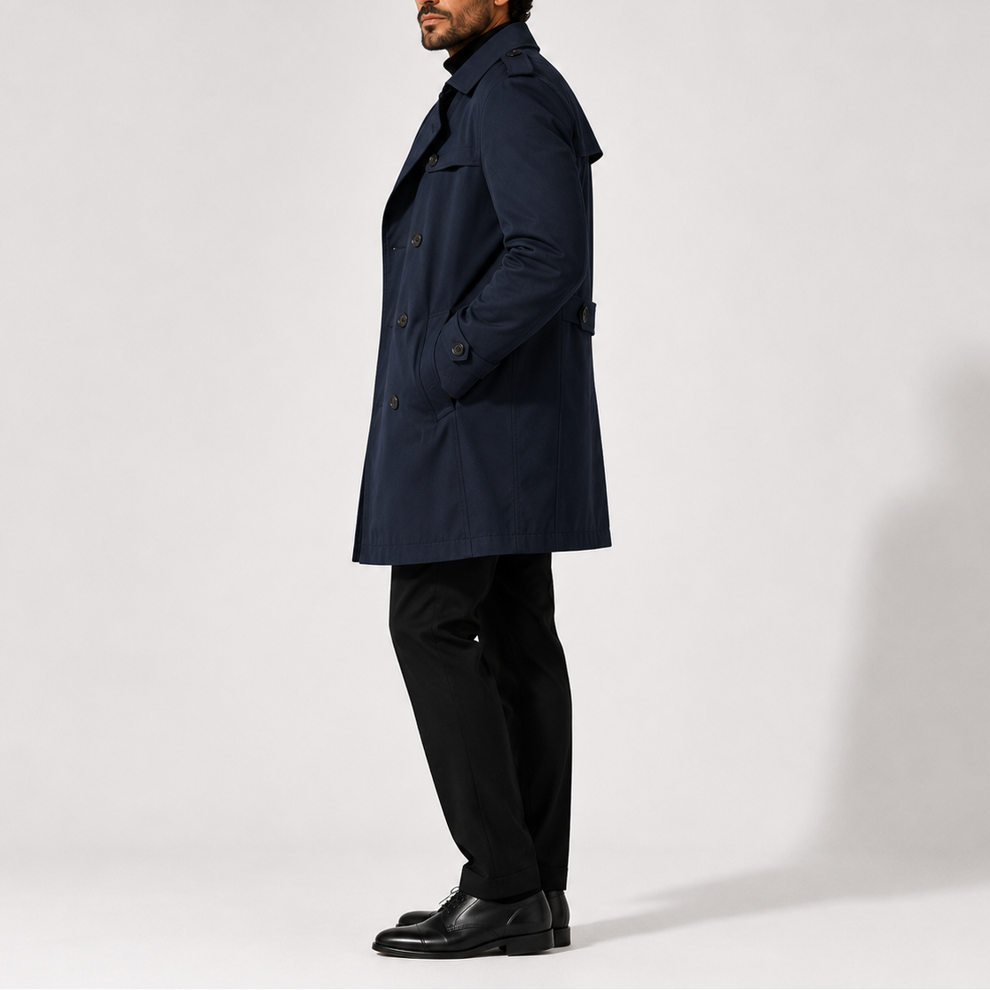 Navy blue mid-length double-breasted trench coat with shoulder epaulettes and structured lapel collar.