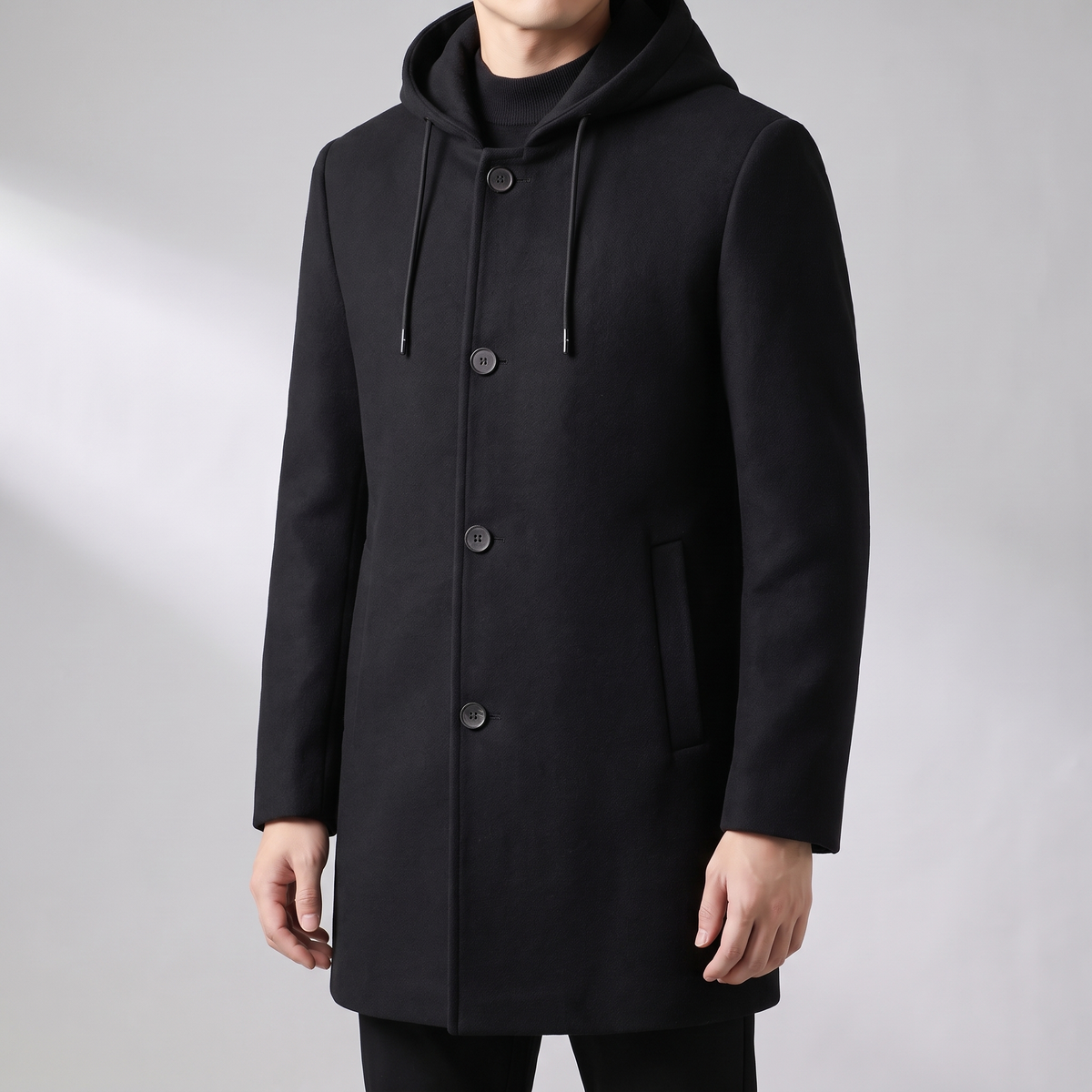 Black wool-blend overcoat with a tailored silhouette, integrated hood, and button-front closure on a neutral background.
