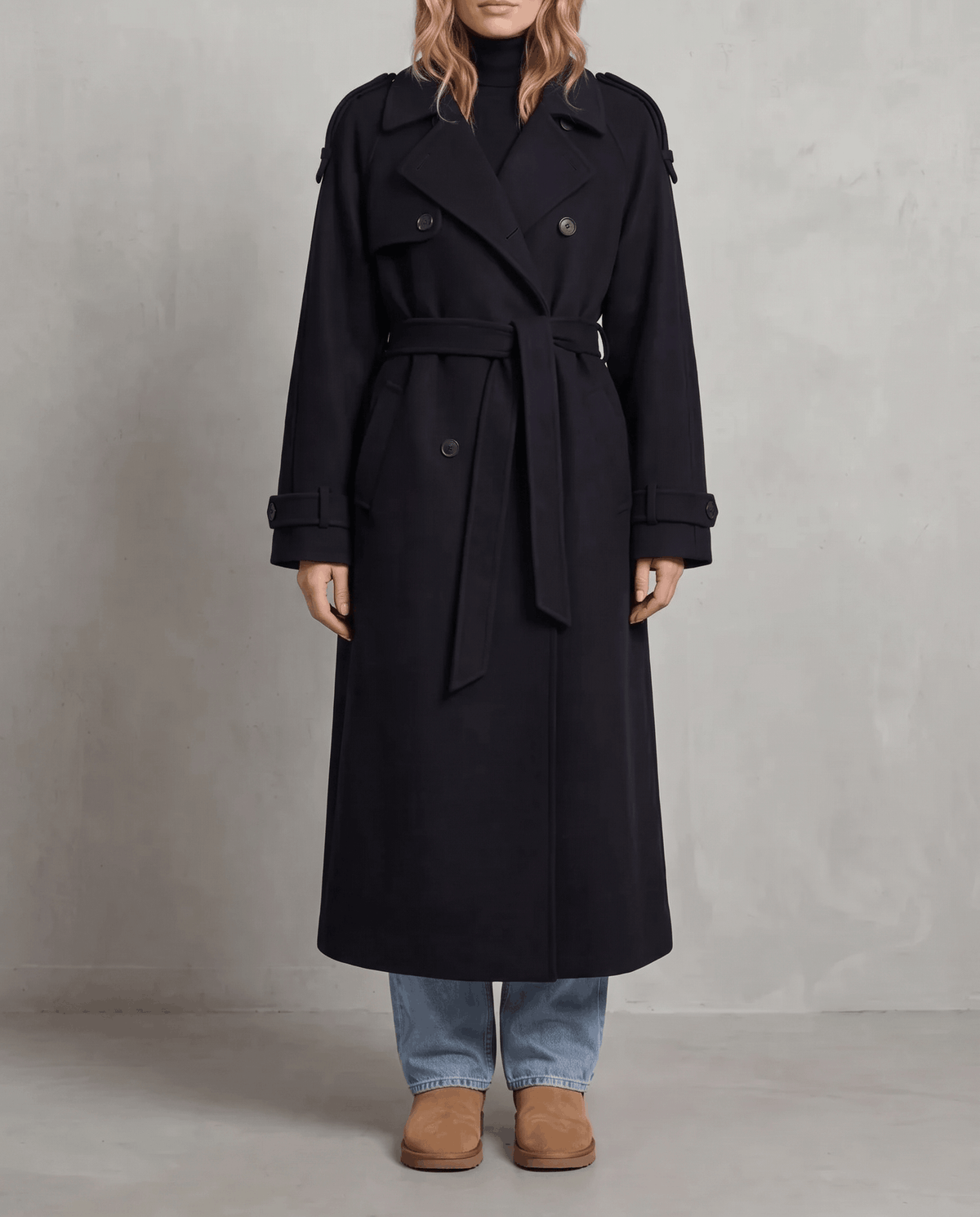 Black wool trench coat in an oversized, longline fit with a double-breasted front and belted waist.