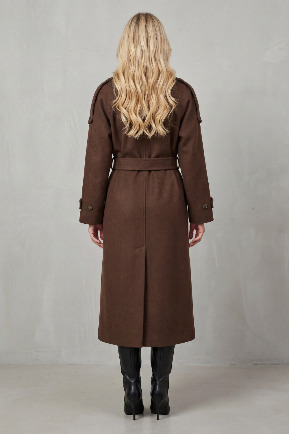 Back view of a brown wool trench coat with a belted waist, longline silhouette, and structured shoulder epaulettes.