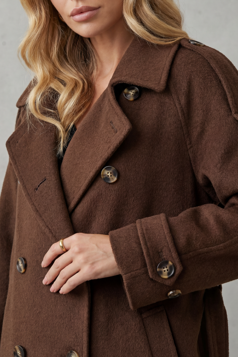 Oversized brown wool trench coat with a double-breasted front, notched lapels, and adjustable cuff straps.