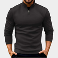 Black half-zip fleece sweatshirt with a stand collar and long sleeves, styled with dark jeans on a white background.
