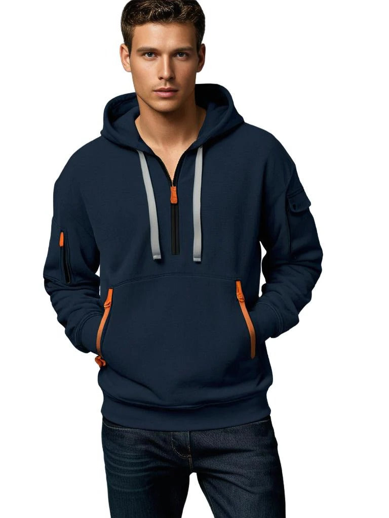 Man wearing a navy tactical hoodie featuring a half-zip neckline, adjustable hood, and contrast zipper details.